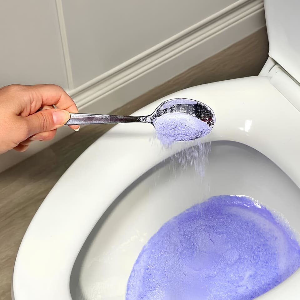 Pouring a scoop of FizzClean powder into the toilet bowl